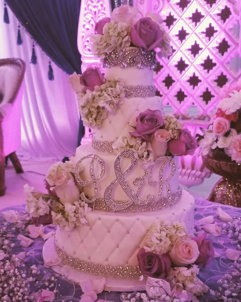 A pink floral wedding cake by AMR Catering, layered with delicate sugar blooms.