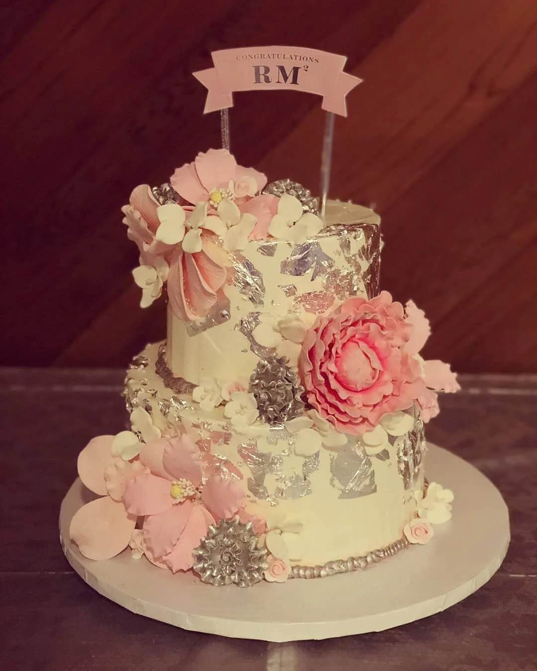 An elegant tiered dessert table by AMR Catering with cake stands of petit fours, dipped strawberries and bite-sized sweets in soft, moody light.