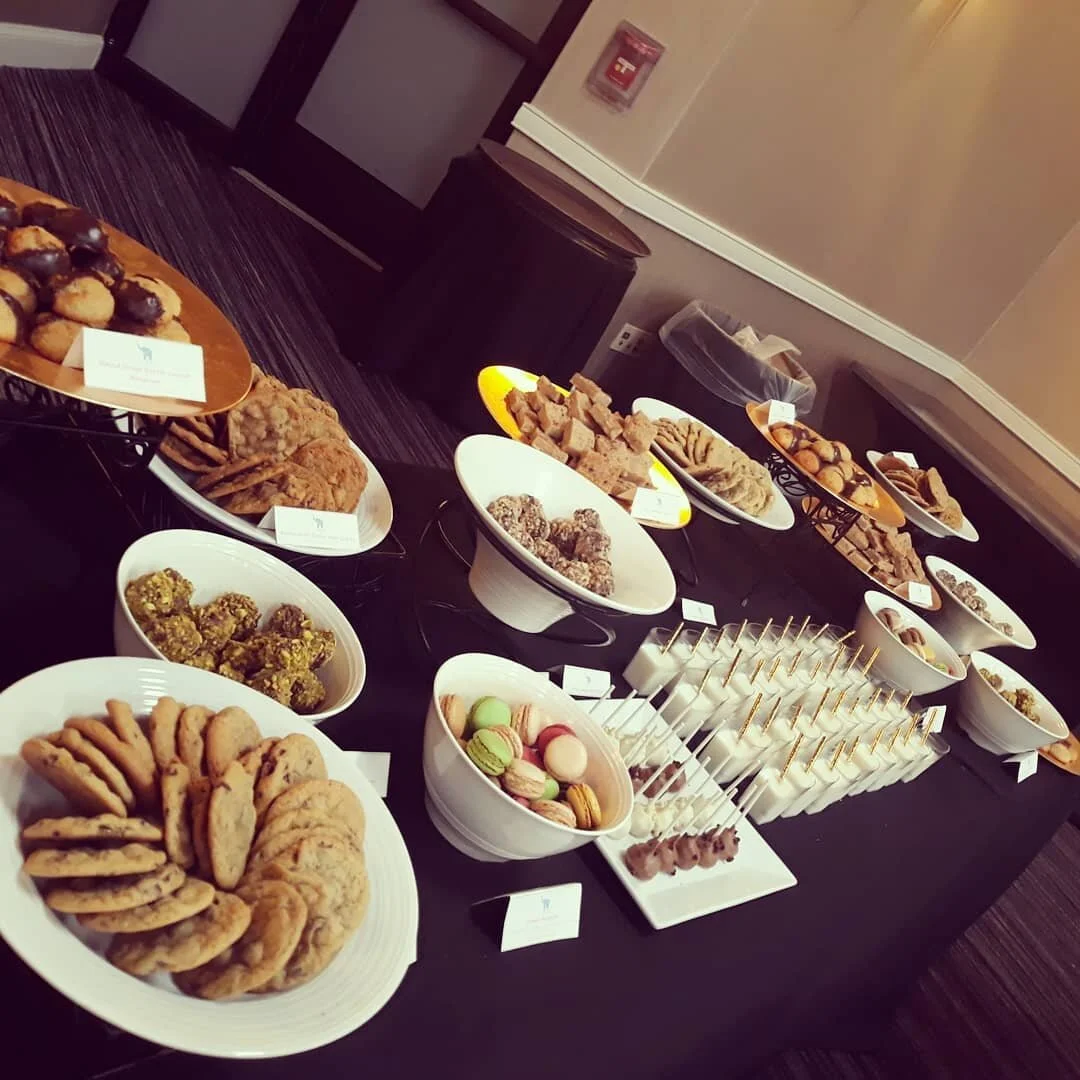 A moody tiered dessert tablescape by AMR Catering with assorted petit fours and bite-sized sweets.
