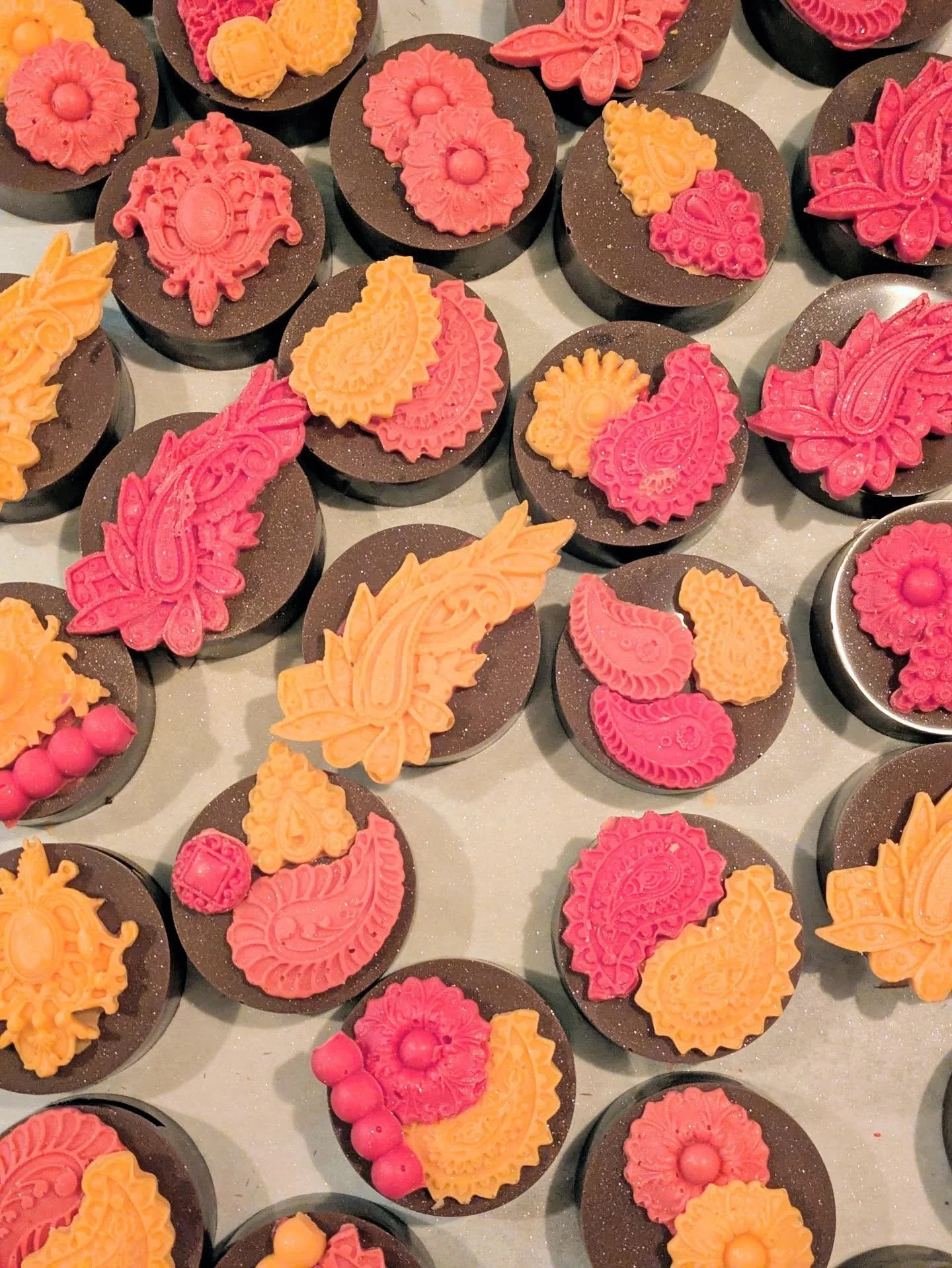 Ornate paisley and mehndi-patterned chocolate favors in magenta and saffron by AMR Catering — the signature American–Indian fusion detail.